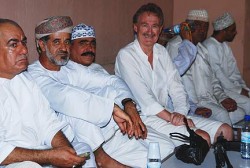 Bob Arno looks up to something as he pretends to relax with men in a souk.