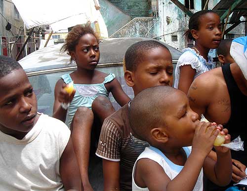 Children surround Bob and the men on the trunk of the car.