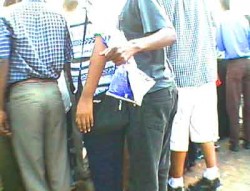 Three pickpockets surround a woman spectator at a car race.