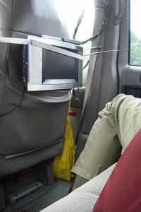 A flat-screen tv is lashed to the back of the seat, its antenna and cable against the window.