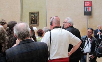 Eiffel Tower pickpockets. A crowd at the Louvre jostle to see the Mona Lisa, ignoring the prominent pickpocket warning.