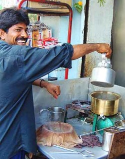 At a tea stall in the Colaba district, the chai-walla pours boiled milk onto tea leaves and spices.