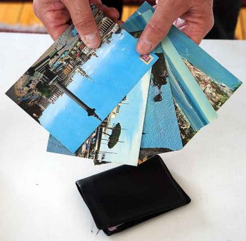 Postcards are offered as if for sale to distracted diners. They're briefly held over a wallet, cell phone, or camera.