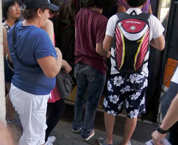 Pickpockets in Pisa: The pickpocket, in blue t-shirt, moves in behind her victim, who is about to board the bus. You can barely see her in the pink dress. The victim's son is in glasses, upper left.