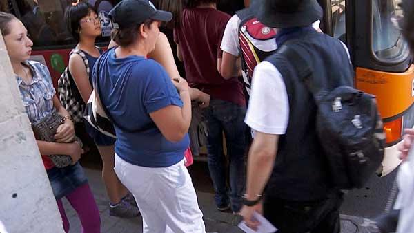 Pickpockets in Pisa: The pickpocket's accomplice (and perhaps her daughter) is in pink tights and plaid shirt. She moves in behind the pickpocket.